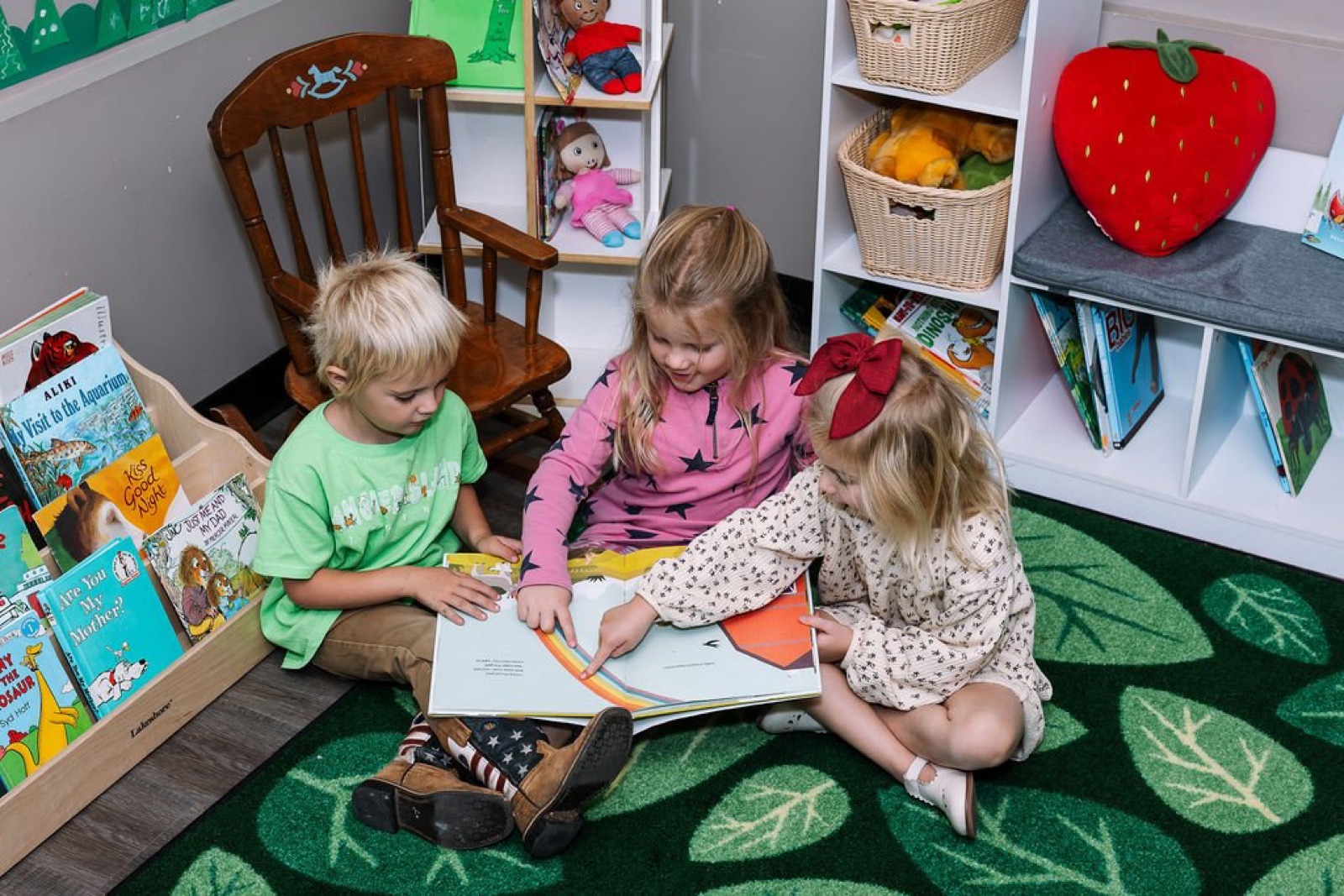 Three children reading a picture book together