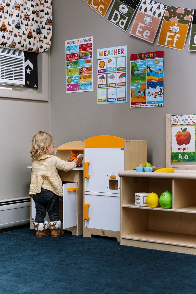 A toddler playing at a child-sized play kitchen